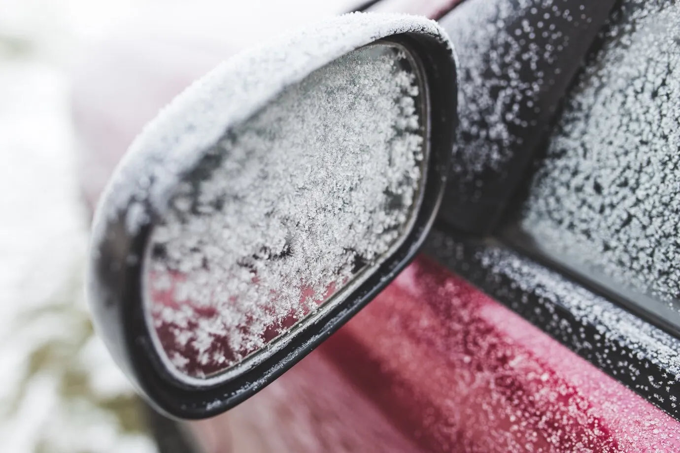Car side mirror and window covered in frost and ice during winter